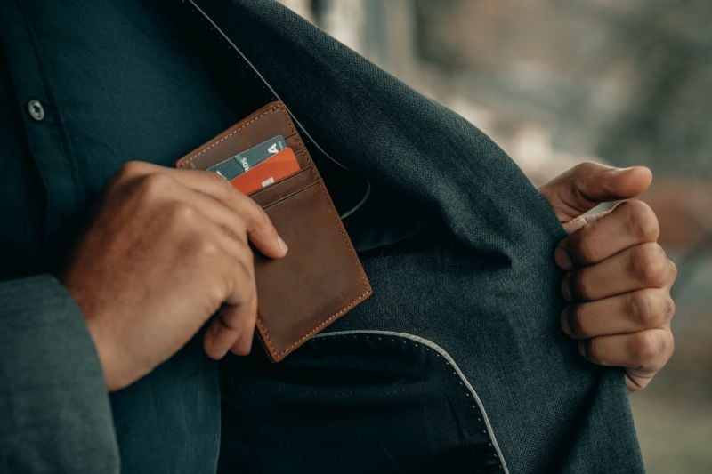 男子拿着棕色钱包和信用卡