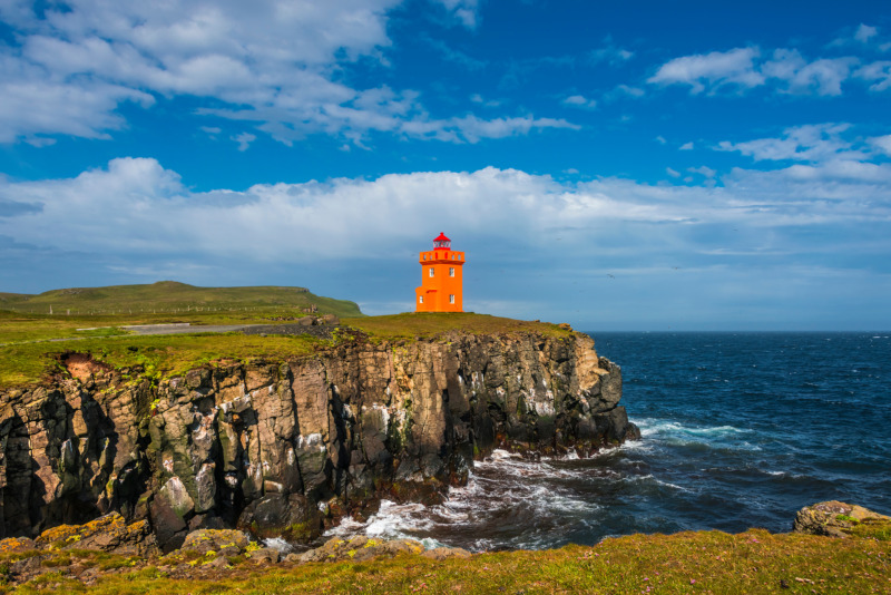 Orange lighthouse at rocky shore of Grimsey Island in Northern Iceland